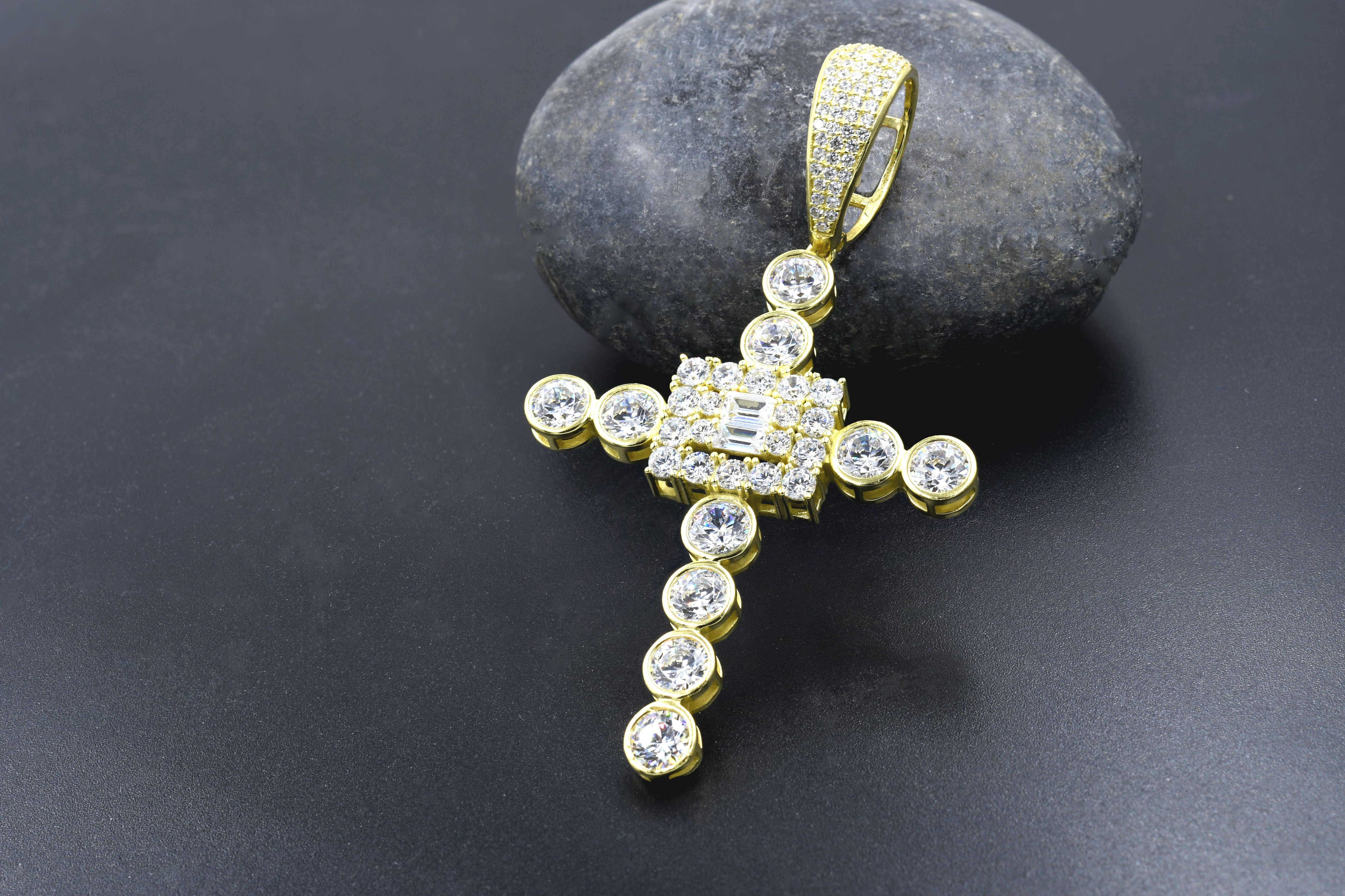 Angelic cross pendant with cubic zirconia from a side angle, highlighting its intricate design.